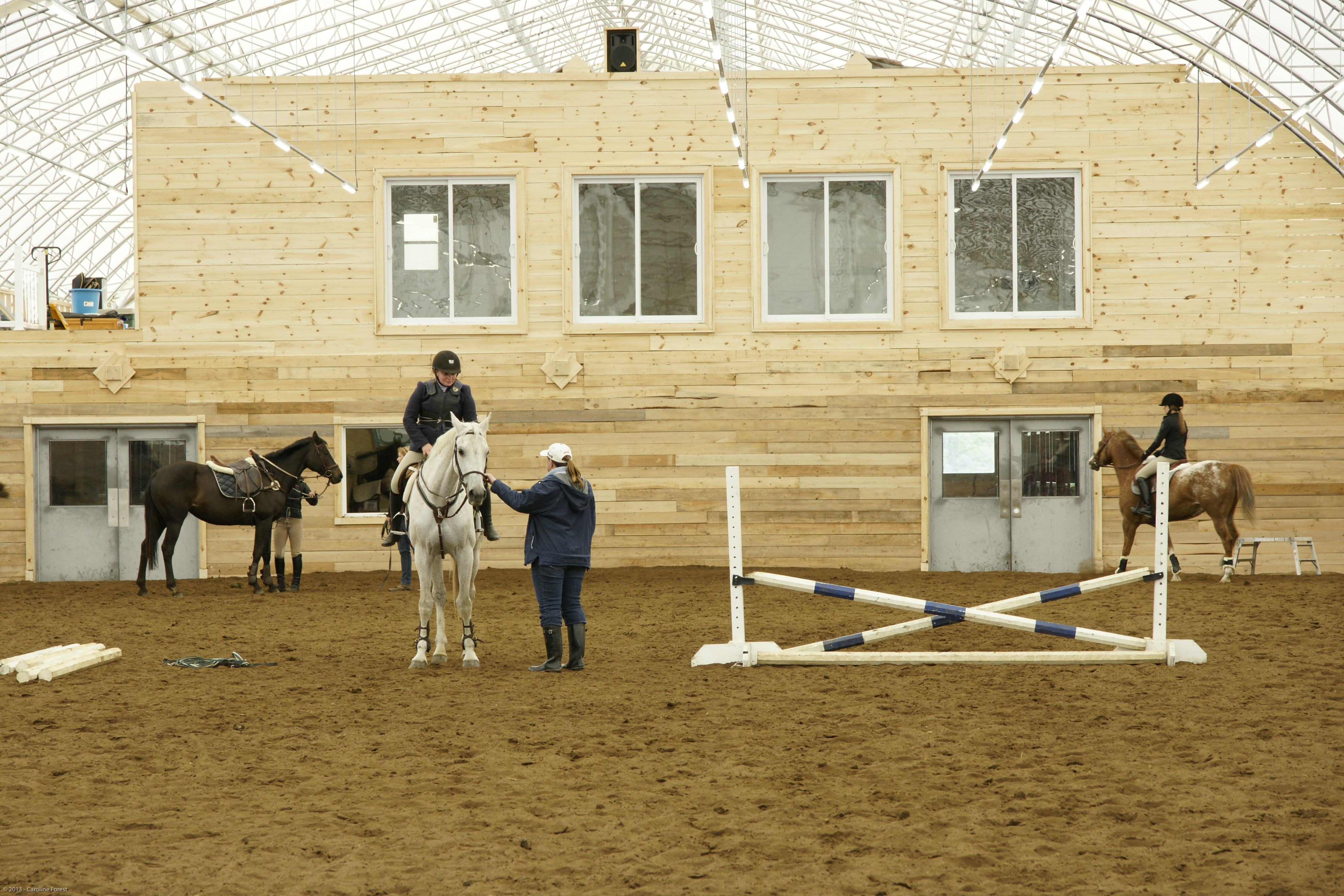 Equestrian riding arena inside a fabric building with riders and natural light