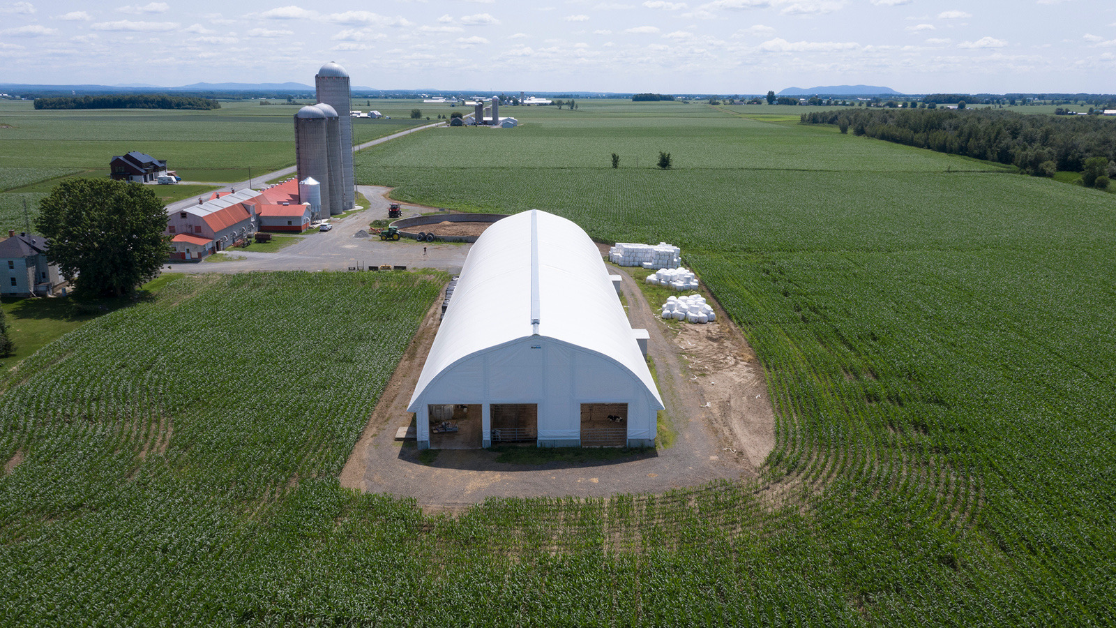 Aerial view of a fabric building on a dairy farm with silos in rural Ontario