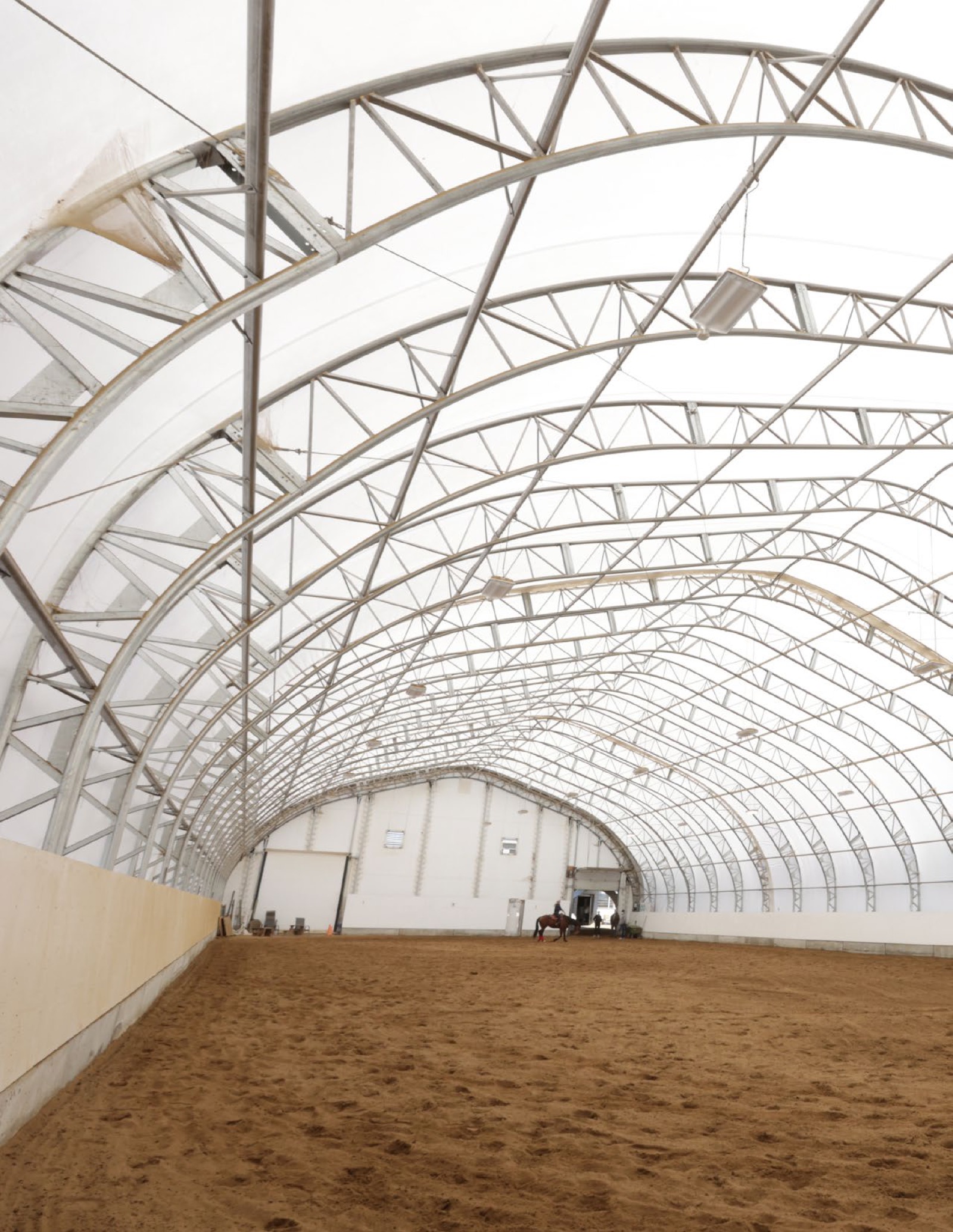 Interior of a fabric building showing galvanized steel trusses and natural light