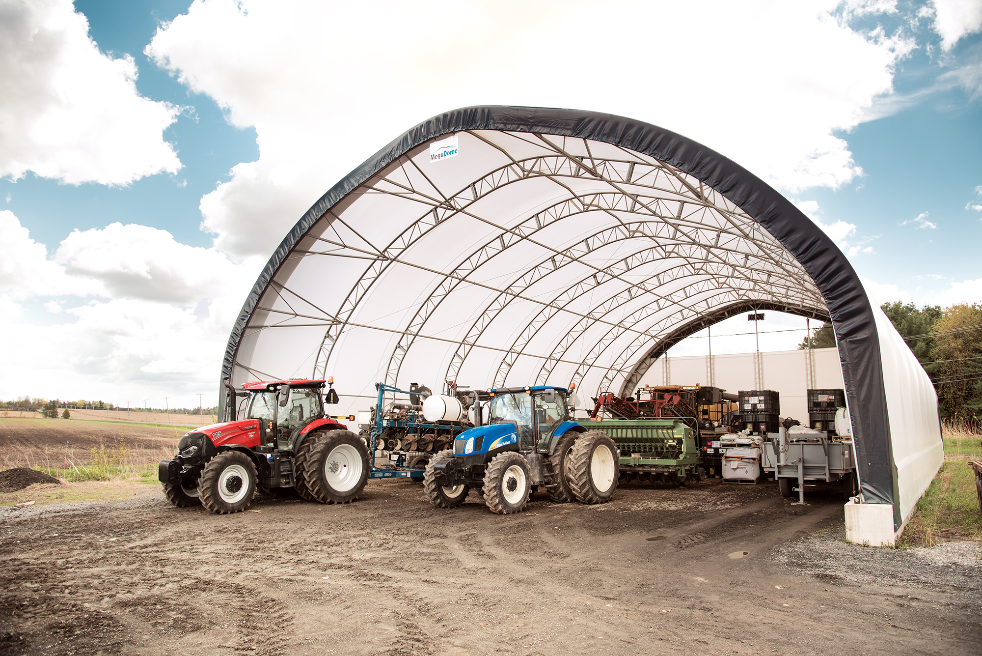 Farm tractors sheltered under a round-profile fabric building