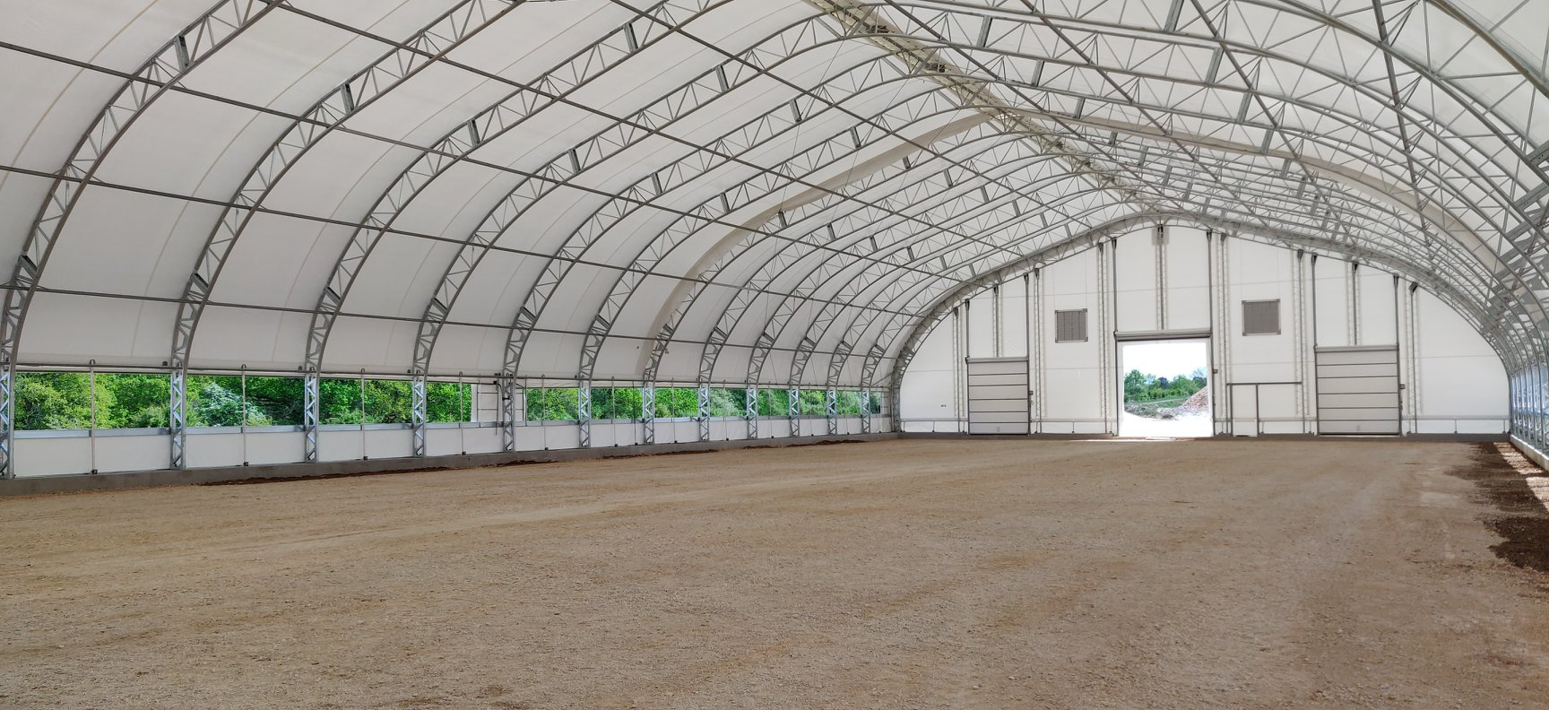 Clear-span interior of a gable-profile fabric building with natural light