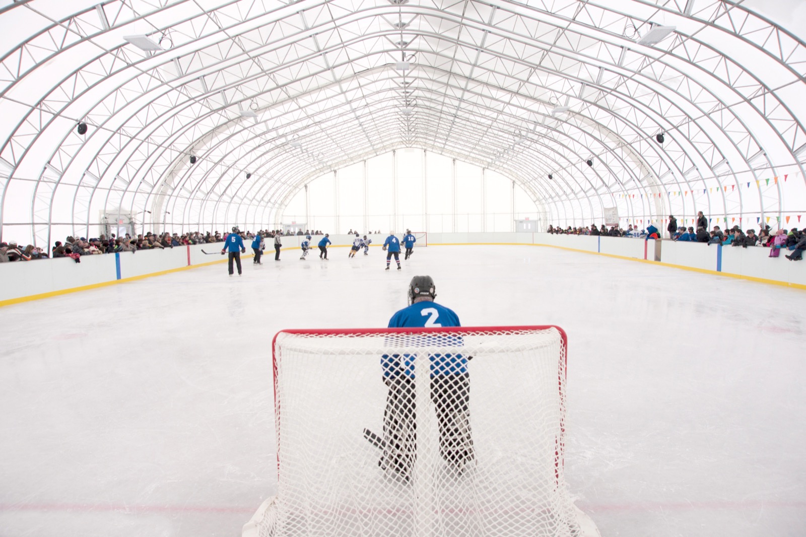 Hockey game inside a community arena fabric building with arched ceiling