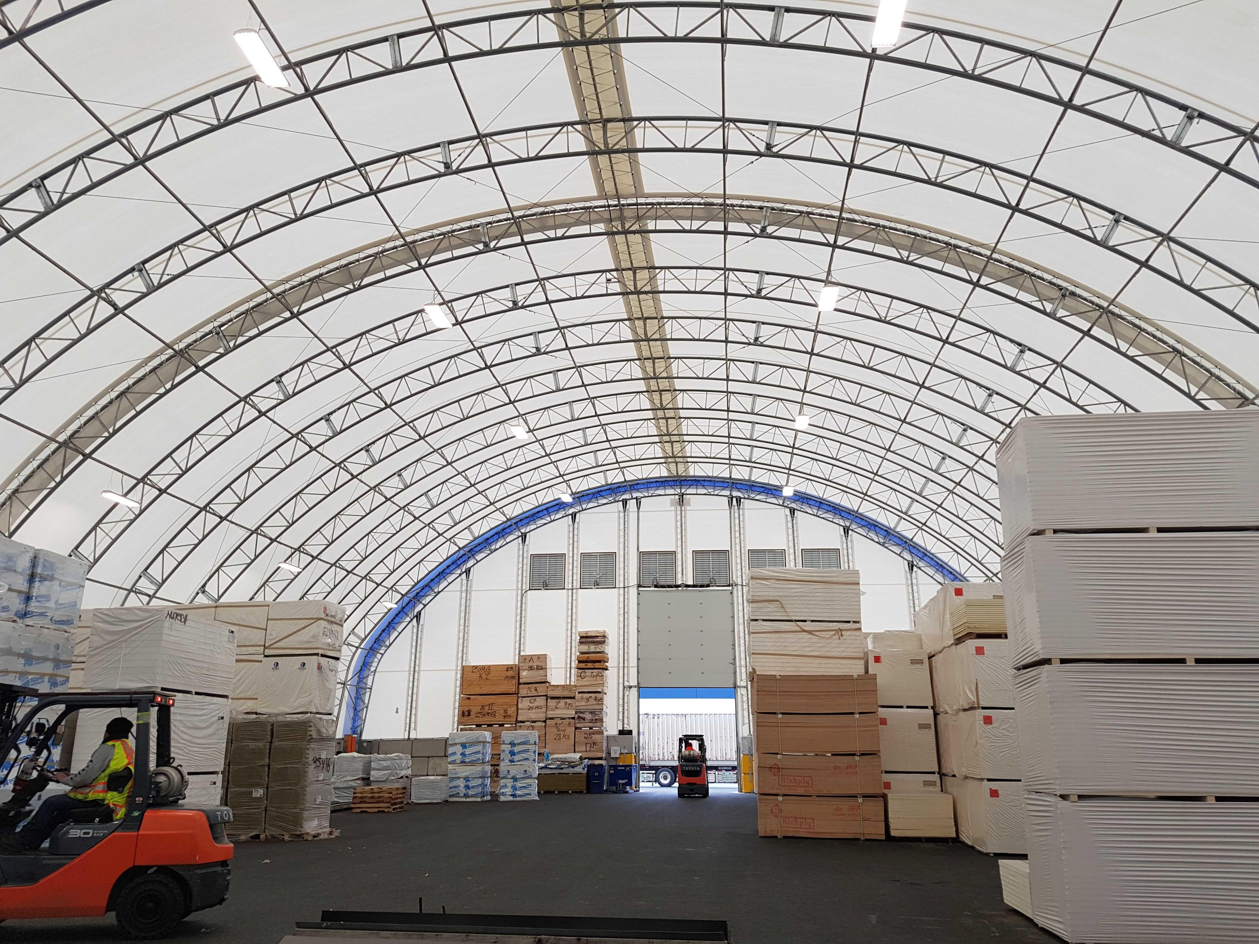 Forklift operating inside a round-profile fabric building warehouse