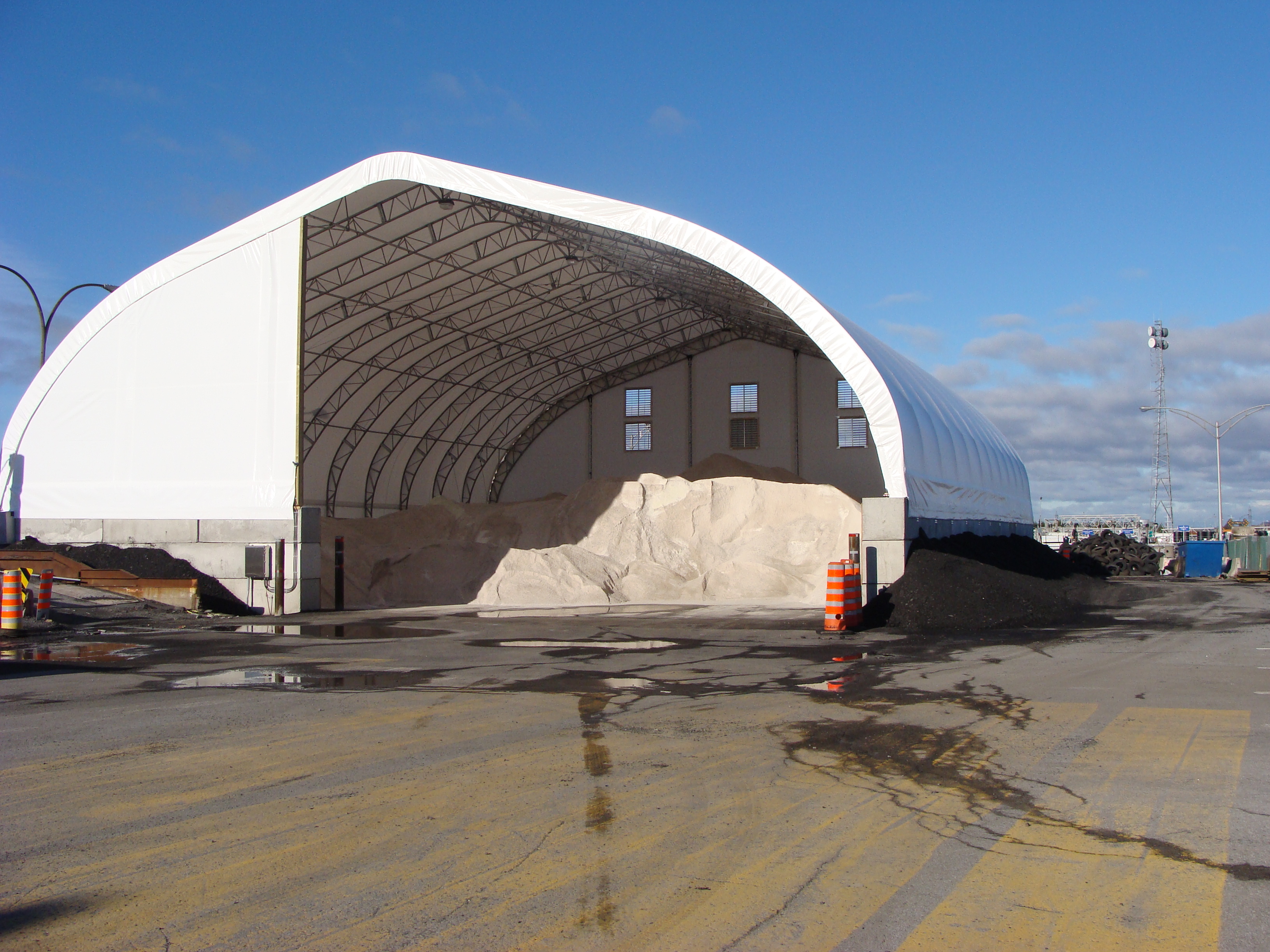 Road salt stockpile inside an open-end fabric building for municipal storage