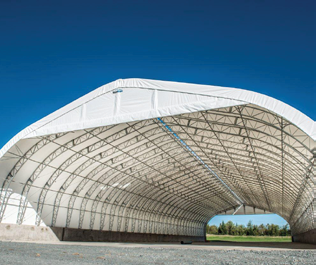 Exterior of a wide-span fabric building showing massive arch opening